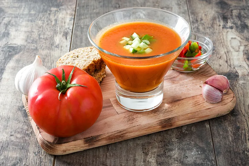 image of a gazpacho with ingredients as decoration around it